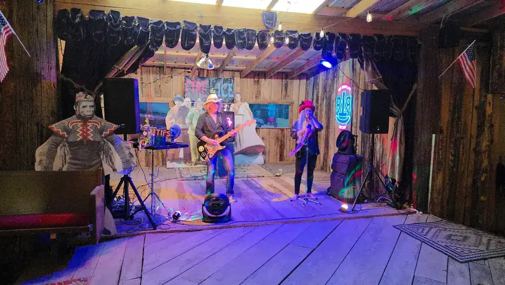 A live band playing on the Rockin' T Ranch barn stage under the RTR neon sign